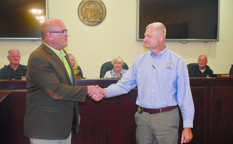 Clarkesville’s new police chief Danny Clouatre (right) shakes hands with City Manager Keith Dickerson at Monday’s meeting. MATTHEW OSBORNE/Staff