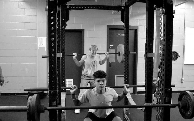 Trey King (front) gets a rep on the squat rack while Canon Wilbanks (back) does an overhead press. ISAIAH SMITH/Staff