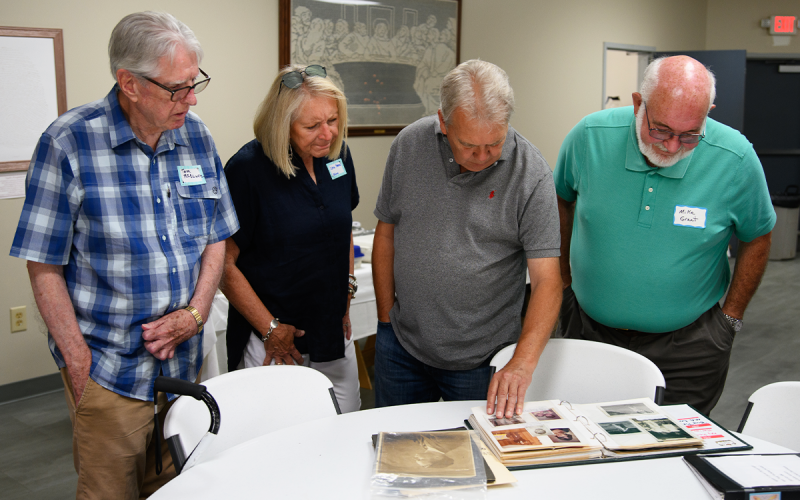From left, Tom McClure, Lana Hames, Jeff Hames, and Mike Grant flip through a photo album that contains photos of their ancestors. ZACH TAYLOR/Special