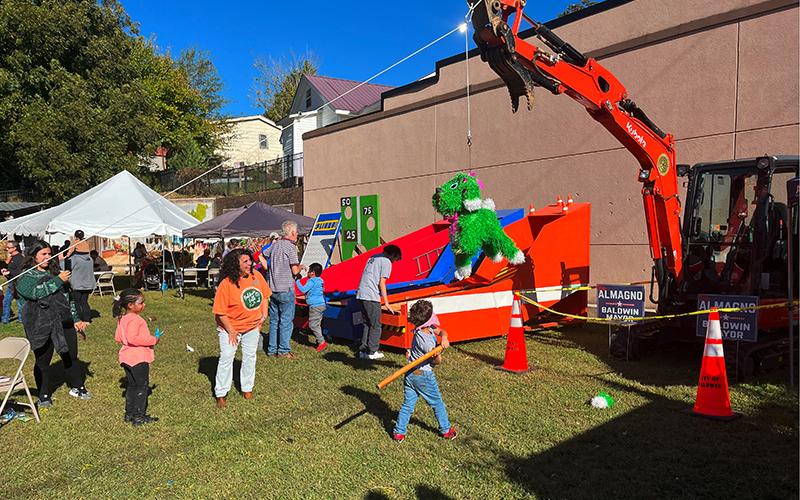 Children take whacks at a pinata at the Baldwin Fall Festival on Saturday. The fun party favor was hanging from a city excavator which was flanked by Stephanie Almagno for Mayor signs. CITY OF BALDWIN/Submitted