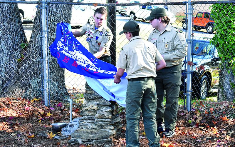 Troop 5 Scouts Keynan Fletter, Zac Baker and Callum Osborne unveil the restored rock water fountain buily by Travis Roseman in 1985 as an Eagle Scout project. MATTHEW OSBORNE/Staff