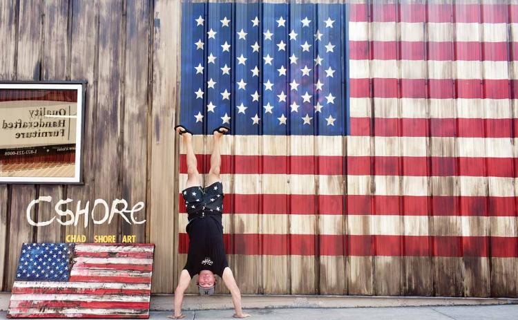 Artist Chad Shore does a headstand in front of his work. (Photo/Chamian Cruz)