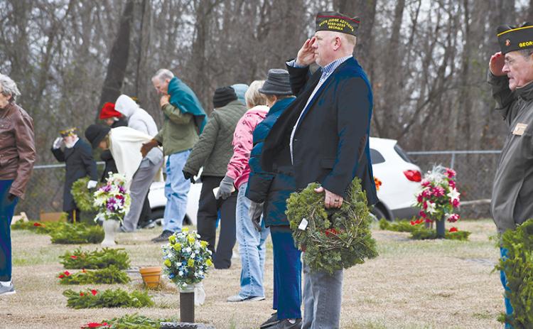 rant-Reeves VFW Post 7720 Commander Bill Miles salutes after placing a wreath on the grave of a veteran at the VFW Memorial Park on Saturday as part of the Wreaths Across America program. Volunteers helped place all the wreaths throughout the cemetery.
