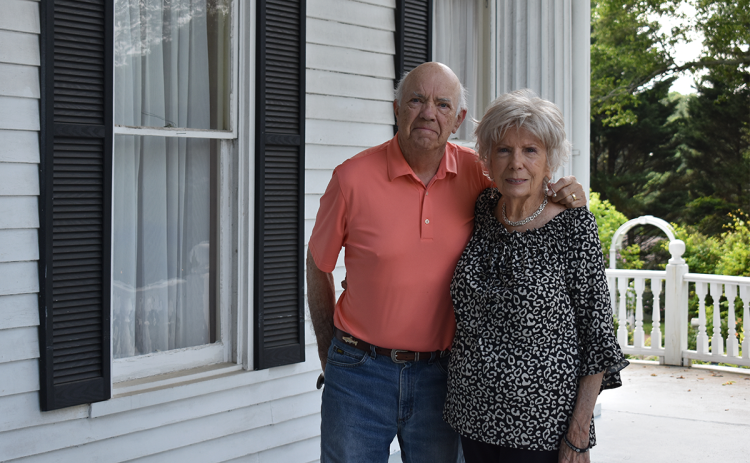 Robert E. “Mitch” and Barbara Mitchell are all smiles standing in front of their new Clarkesville home. Even though they won’t be full-time Clarkesville residents for a little while, they are excited for the progress to begin. EMMA MARTI/Staff