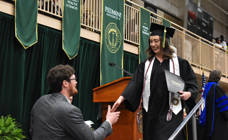 Samantha Carvallo takes a helping hand from digital marketing manager Zack Hoopaugh after receiving her degree Friday at Piedmont University’s graduation ceremony. Carvallo graduated with a Bachelor of Arts degree and majored in art during her time at Piedmont. EMMA MARTI/Staff