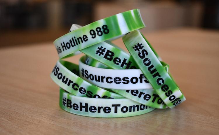 A stack of bracelets created by students in Sources of Strength, printed with the group’s names, Kevin Hines’ slogan, and the 988 Suicide and Crisis Lifeline. JULIANNE AKERS/Staff