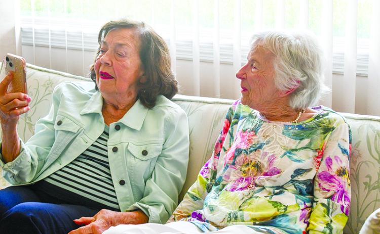 Betty  Dalton (left) and Wilma Propes check out a picture on a cell phone at Dalton’s home in Baldwin. JULIANNE AKERS/Staff
