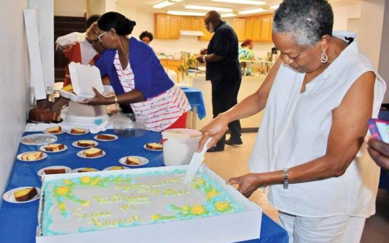 Gwen Brown, daughter of Susie Brown, cuts the cake at Susie Brown's 100th birthday party earlier this month at a Clarkesville church.