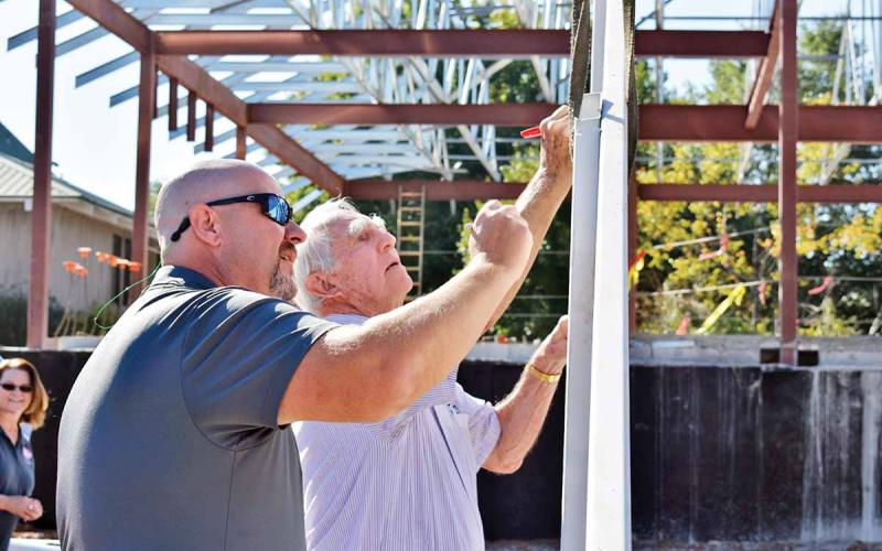 Cornelia City Manager Donald Anderson, left, and Cornelia Mayor James C. “J.C.” Irby ink their signatures on the final beam before it’s placed atop the city’s new municipal complex during a topping-out ceremony Friday, Sept. 6, at the site. (Photo/CHAMIAN CRUZ)