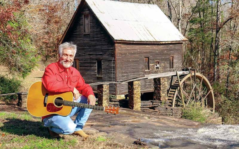 Musician Danny Thomas poses with his guitar in front of Ragsdale Grist Mill in Homer (Banks County).