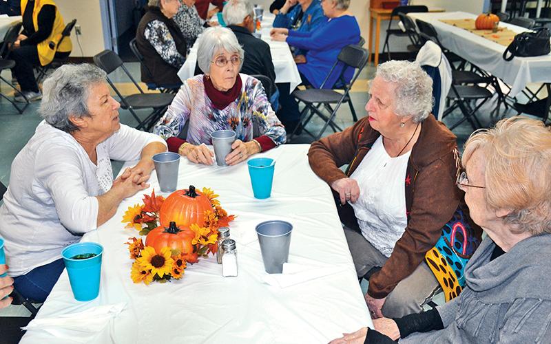 Karen Katz, Patsy Edwards, Barbara Land and JoAnn Cross (clockwise from left) converse just before the Thanksgiving meal at the Habersham County Senior Center on Friday. The friends were part of a record crowd at the meal with more than 140 guests.