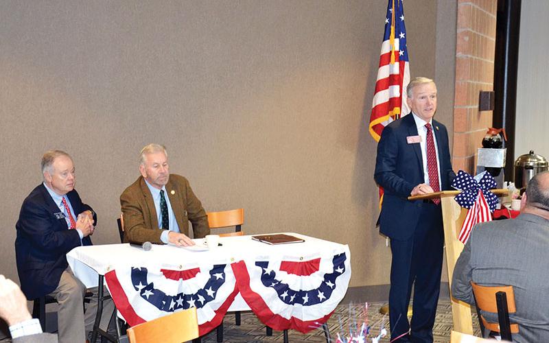 Georgia Rep. Chris Erwin speaks at the dais while fellow legislators Sen. John Wilkinson (left) and Rep. Terry Rogers wait their turns to speak at Tuesday’s legislative breakfast at North Georgia Technical College.