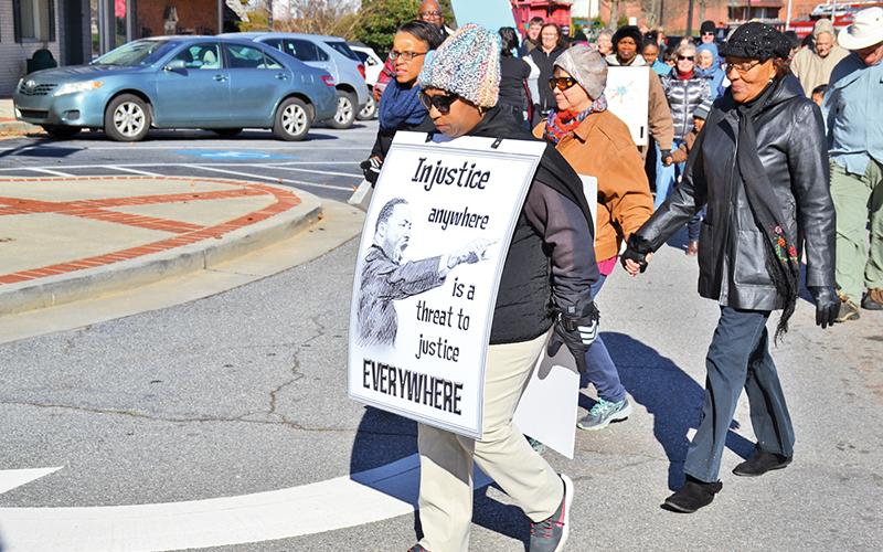 Jeanette Fuller led the way during the Peace Walk and kept her sign in place despite strong winds.