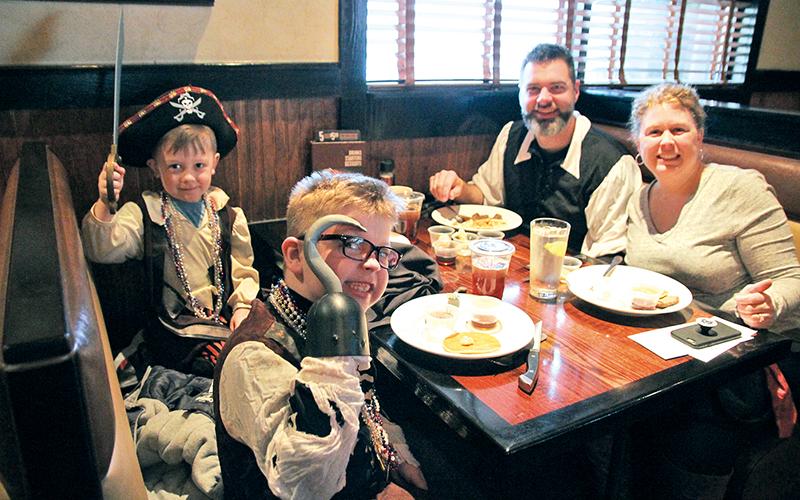Cohen Thomas, 4, Collier Thomas, 7, Dustin Thomas and Leigh Thomas gather for a pirate family feast Saturday morning.