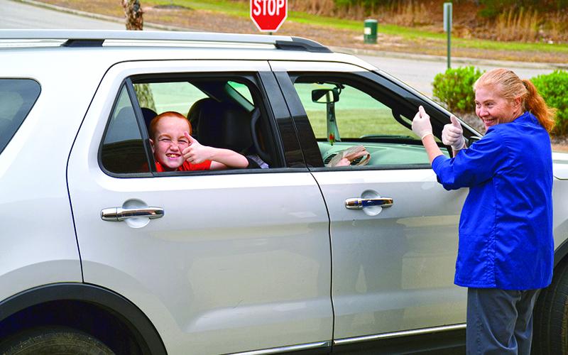 Fairview Elementary student Dennis Harkins gives Malinda Lathan and other school nutrition associates a thumbs up during the meal pickup at Fairview Elementary on Thursday. Free meals for students 18 and under are available at all elementary schools in Habersham County Monday through Friday from 11:30 a.m. to 12:30 p.m. Photo by ALAN NESMITH