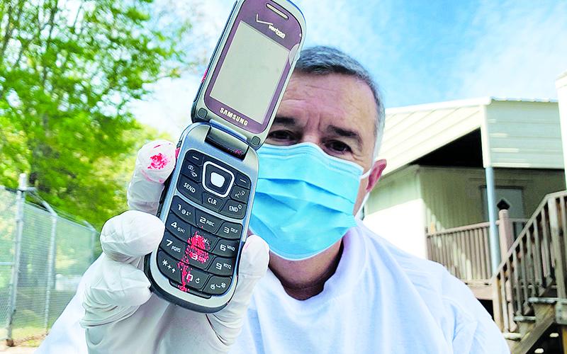 Habersham County Emergency Services Director Chad Black demonstrates in a public service video Wednesday how wearing gloves can cross contaminate personal items, such as a cell phone, using fingerprint powder.