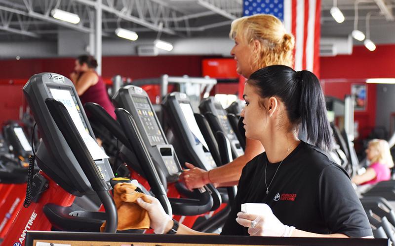 Ariel Coones, a trainer at Workout Anytime in Cornelia, sanitizes one of the many ellipticals. The staff plans to regularly clean the gym equipment now that members have returned.