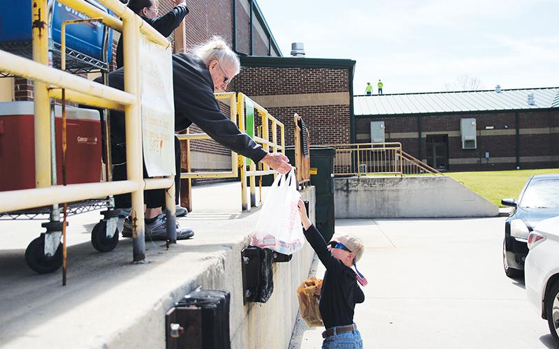 Demorest Elementary School nutritionist Mary Edder hands out meals to McCoy Wilson during Wednesday’s lunch pickup. Photo by Eric Pereira