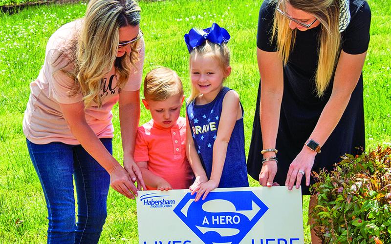 Jessica Little, Dallas Little, 6, Cash Hester, 3, and Kristen Hester place a “hero” sign in front of a Clarkesville home on Monday. The signs are part of an effort to recognize and thank healthcare workers who are working on the “front lines” of the current COVID-19 pandemic.