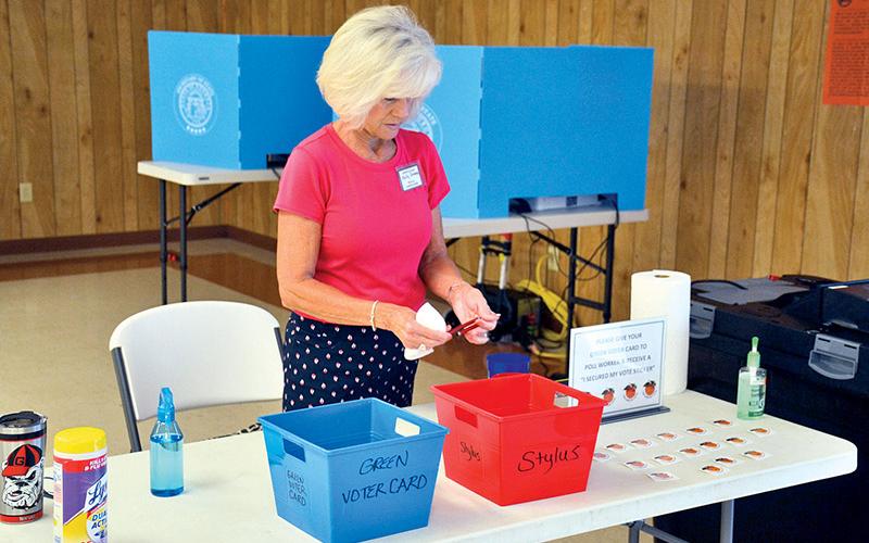 Poll worker Kelly Greene cleans voting materials Tuesday morning at B C Grant Baptist Church in Baldwin.