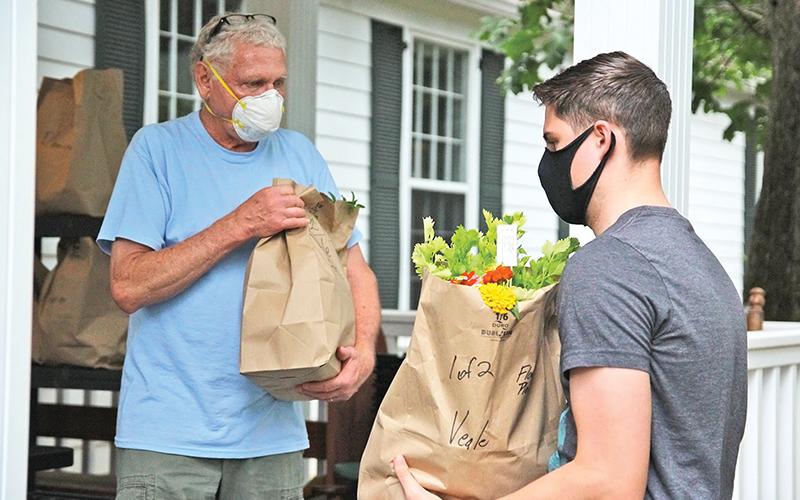 Carson Veale (right) from Clarkesville picks up his Northeast Georgian  Locally Grown produce with the assistance of volunteer Tom Gagnon. Locally grown foods have seen a surge during the pandemic crisis.