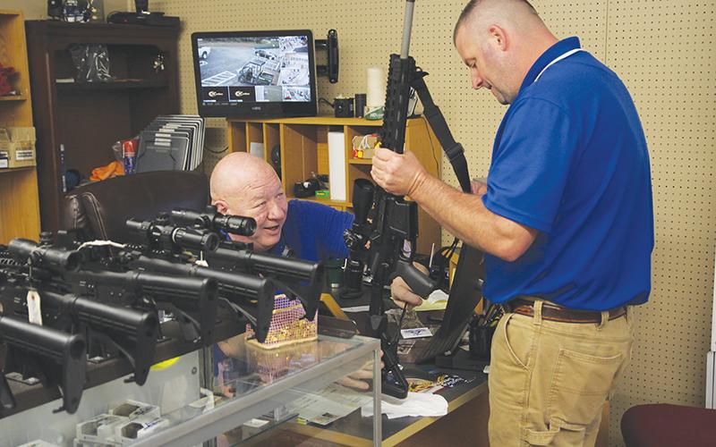 Country Boy Sports owner Kerry Stephens assists customer Kipp Dowdy with the purchase of his new rifle.