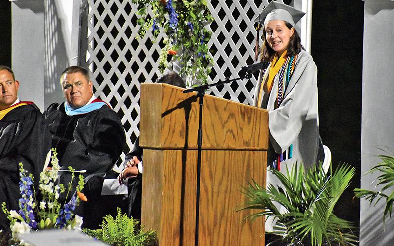 Valedictorian Grace Wills delivers her address as school board member Doug Westmoreland looks on.