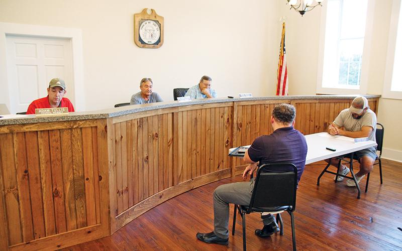 Mt. Airy Council members Adam Tullis, Ray McAllister and Mayor Pro-Tem Mike McCoy discuss the town millage rate Wednesday night. Seated below are councilmen Patrick Leford and Chris Green.