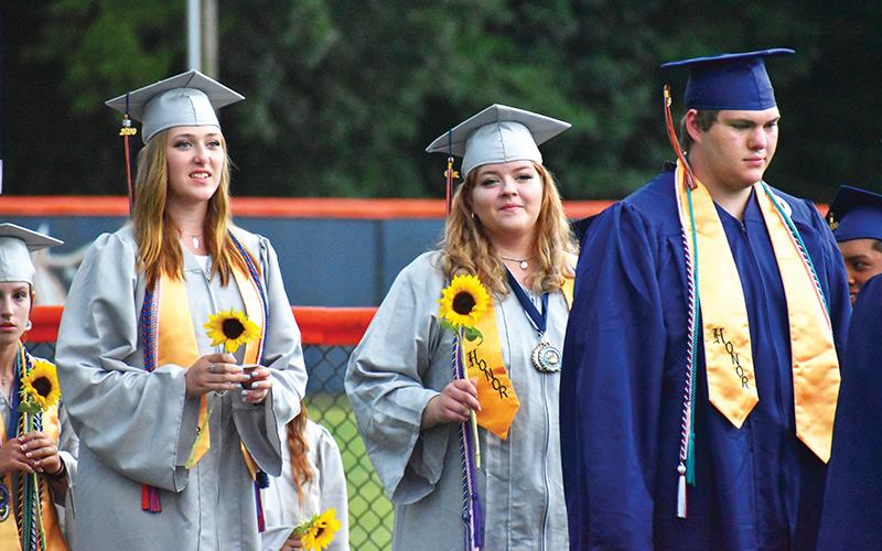 Habersham Central graduates (from left) Rachel Jenkins, Ellawyn Ketch and Nathan Luders prepare to walk onto John Larry Black Field on Friday night for the graduation ceremony. Below, many graduates decorated their caps with messages.