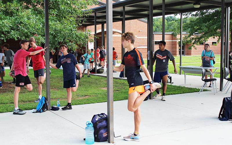 Along with being its top finisher in each race, he also leads stretches  (below foreground) and takes time to help teammates become better runners too.