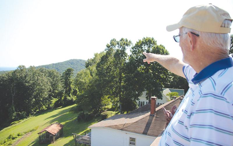 Walter Looney points to some of the sights from the widow’s walk of the home he stripped to the studs before rebuilding.