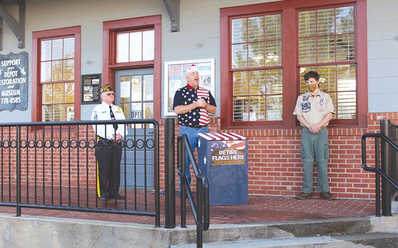 Bill Miles speaks during the flag box dedication ceremony while Chris Egeland (left) and Joseph McNair (right) watch.
