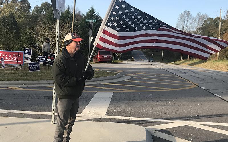 A man who described himself only as a "proud American" waves Old Glory in front of the Ruby Fulbright Aquatic Center on Tuesday morning as folks came to vote.