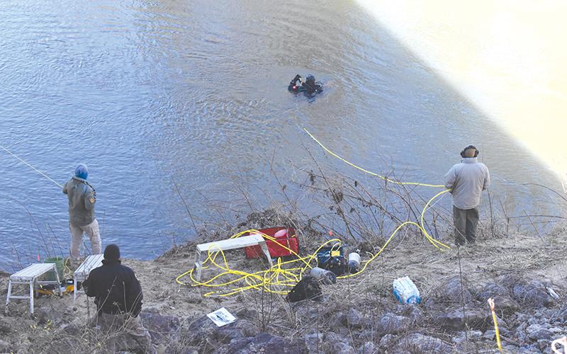 Officers from Georgia State Patrol monitor divers in the Chattahoochee River on Thursday afternoon as they search for the missing gun in a Jan. 18 shooting.