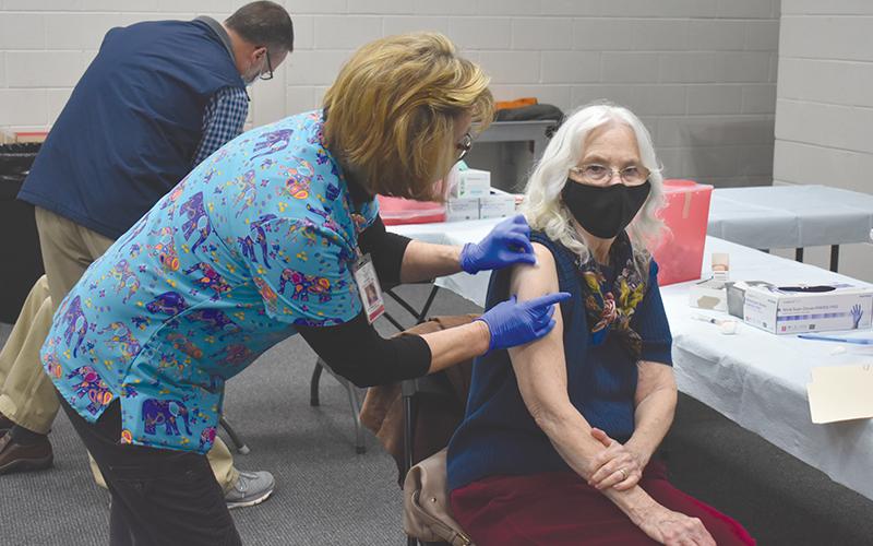 Pennie Ansley, a registered nurse with the Habersham County Health Department, administers the second dose of the COVID-19 vaccine to Marcia Brazinski on Wednesday. The vaccination took place at the Ruby Fulbright Aquatic Center in Clarkesville. Her husband, Franklin Brazinski, sits behind her.