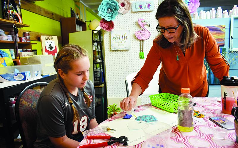 Splashe PYOP Art Studio Owner Valerie Wheeler, right, helps Blair Huddleston during a glass fusing class.