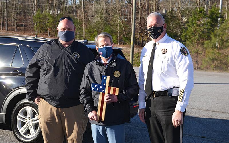 Deputy Justin Williams (left) and Sheriff Joey Terrell (right) present a cross designed by Williams to Gov Brian Kemp as a gift on Monday morning.
