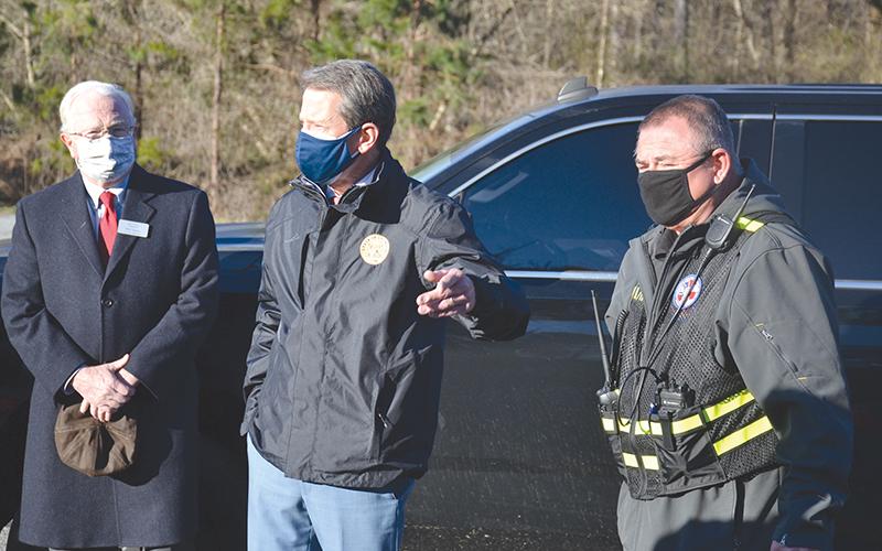 Gov. Brian Kemp speaks during his Monday morning visit to the fairgrounds as County Manager Phil Sutton (left) and GEMA site manager Donald Strength (right) listen.