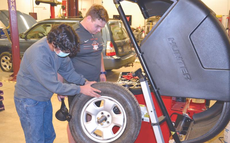 Habersham Central student Landen LaPrade (right) and Carlos Mora check the balance of a tire on a new machine added to the school’s automotive workshop Wednesday. MATTHEW OSBORNE/Staff