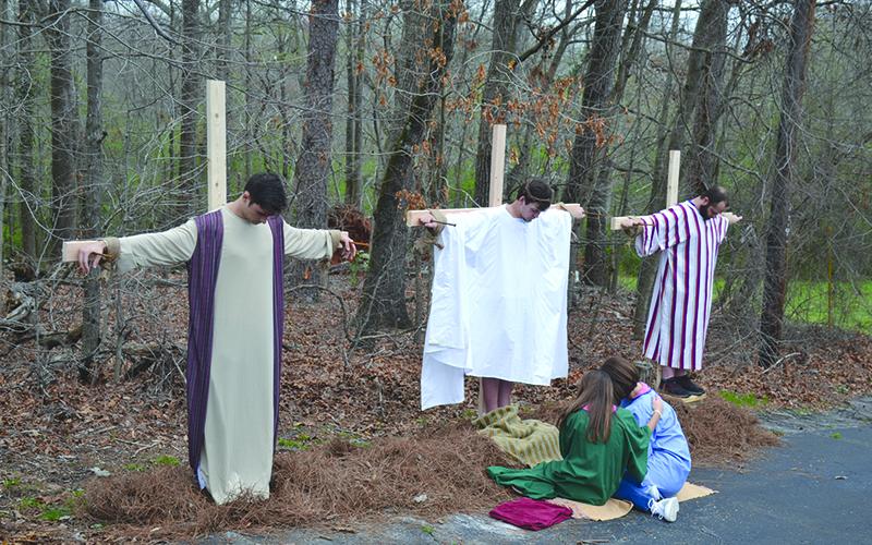 Participants in the drive-through Easter display at Mt. Carmel Baptist Church in Demorest on  Saturday morning included (on  crosses, from left) Jairus Spurlock, Ethan Pruitt and Matthew Graham. On the ground are Madison and Jana Ward.