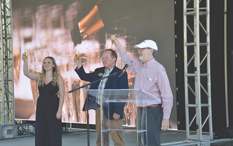 Piedmont University graduate Caitlin Fisher, Vice President for Marketing and Communications John  Roberts and President James Mellichamp toast the new christening of the school as a university Wednesday with sparkling apple juice.