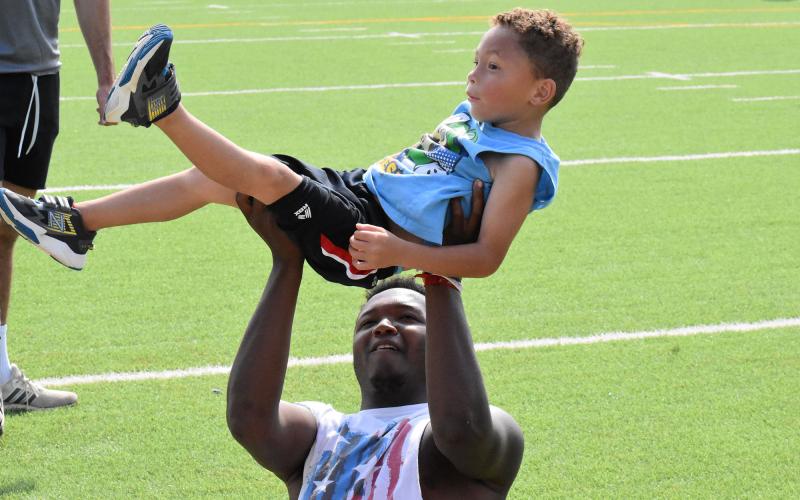 Alex Aaron (bottom) lifts a young camper between stations Tuesday. ISAIAH SMITH/Staff