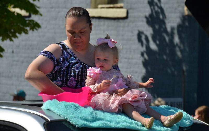 Magnolia Carney and her mom ride in style on top of a car during the parade Saturday morning. MATTHEW OSBORNE/Staff