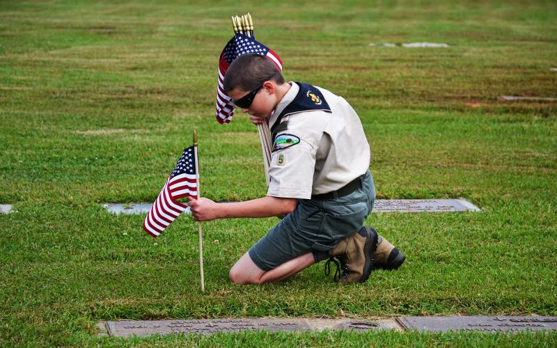 Finn Jackson of Boy Scout Troop 5 in Clarkesville places flags on the graves of veterans Thursday morning at the Veterans of Foreign Wars Memorial Park in Demorest. MATTHEW OSBORNE/Staff