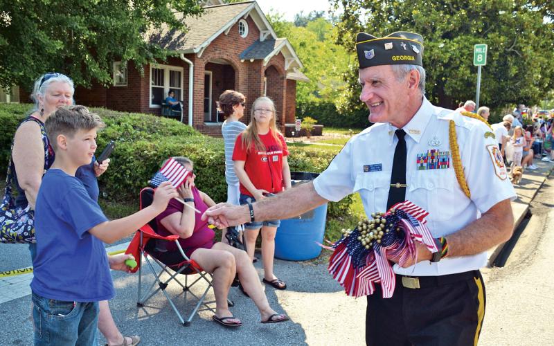 Rick Chaffon gives a flag to Hunter Hill during the parade at the 2019 Mountain Laurel  Festival. FILE