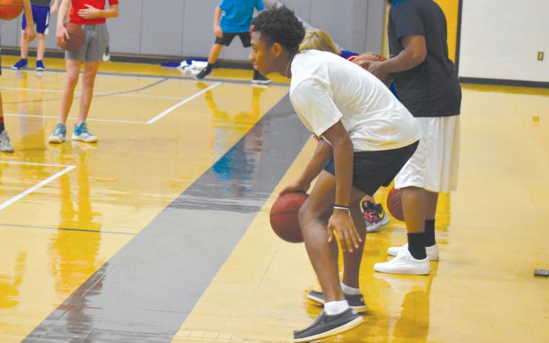 Malachi Dooley has been a special guest at camp all week. Here, Dooley demonstrates a dribble move for campers. ISAIAH SMITH/Staff