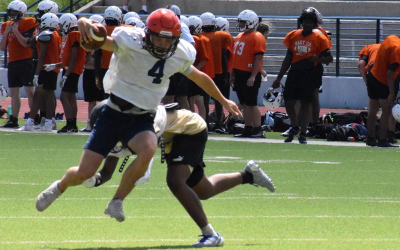 Carson Parker eludes a diving East Hall defender during a scramble during the Raiders’ padded team camp Wednesday. ISAIAH SMITH/Staff