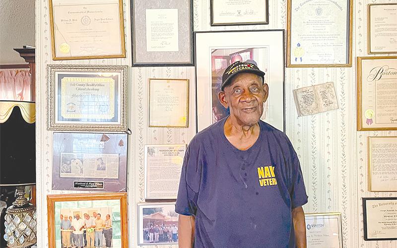 Mordecai Wilson stands by the many awards that adorn the wall of his Lula home.