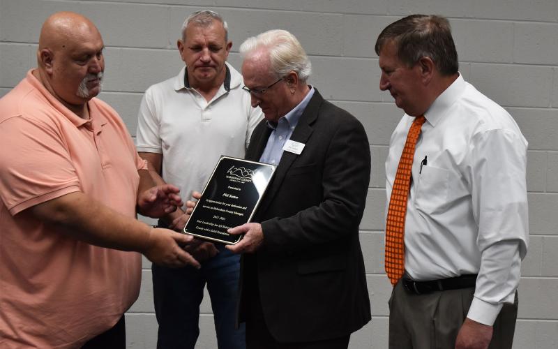 Phil Sutton receives a plaque from Habersham County Commissioners Bruce Palmer (left) and Bruce Harkness (right), along with former commissioner Tim Stamey, at a ceremony Friday. MATTHEW OSBORNE/Staff