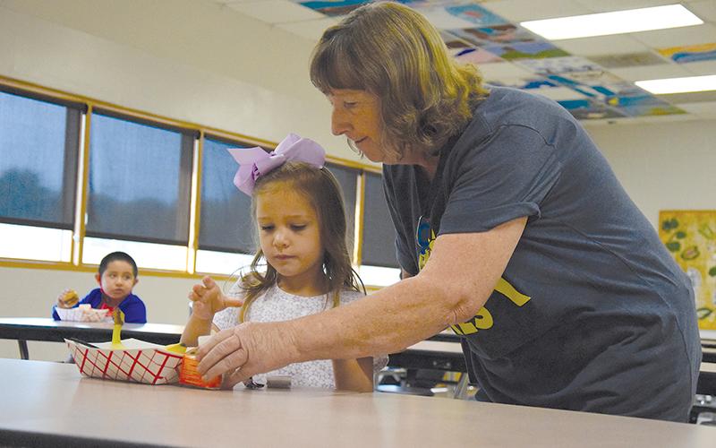 Above, Clarkesville Elementary custodian JoAnn Oliver helps kindergartener Lily Ellison get her breakfast. SAMANTHA SINCLAIR/CNI News Service